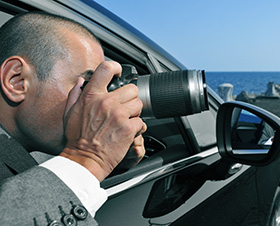 Man in a car taking pictures while being a Private investigator in Charlottesville